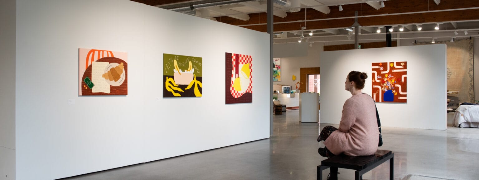 Nainen istuu galleriassa taidetta katsomassa.