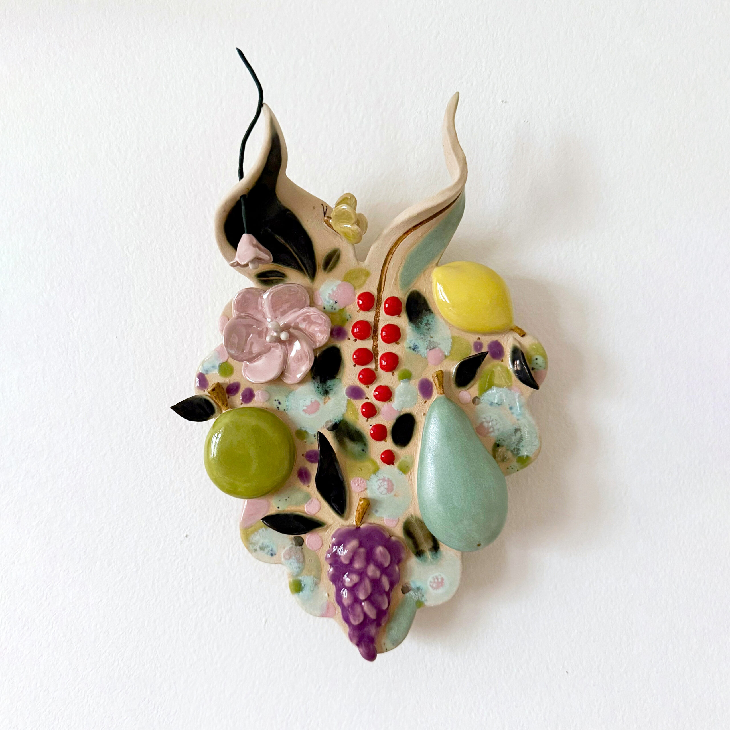 Värikäs keramiikkakoriste hedelmäaiheilla seinällä.