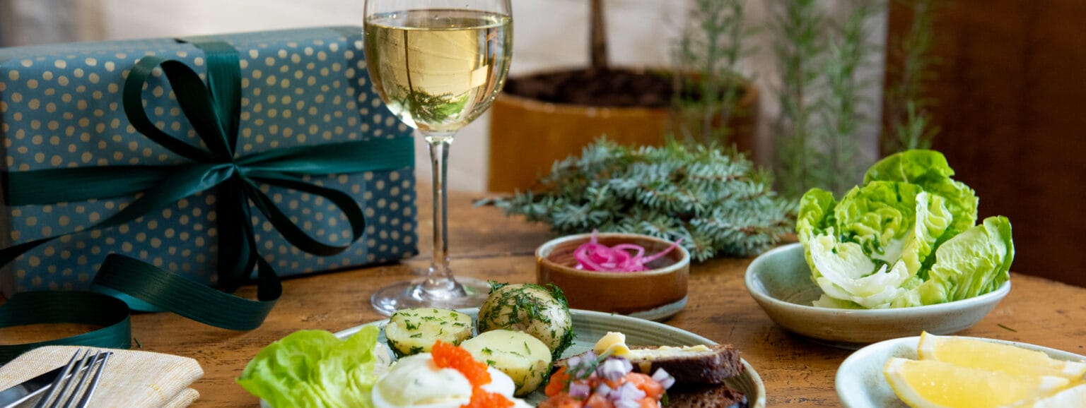 Lounaslautanen viinin ja lahjan kanssa pöydällä.
