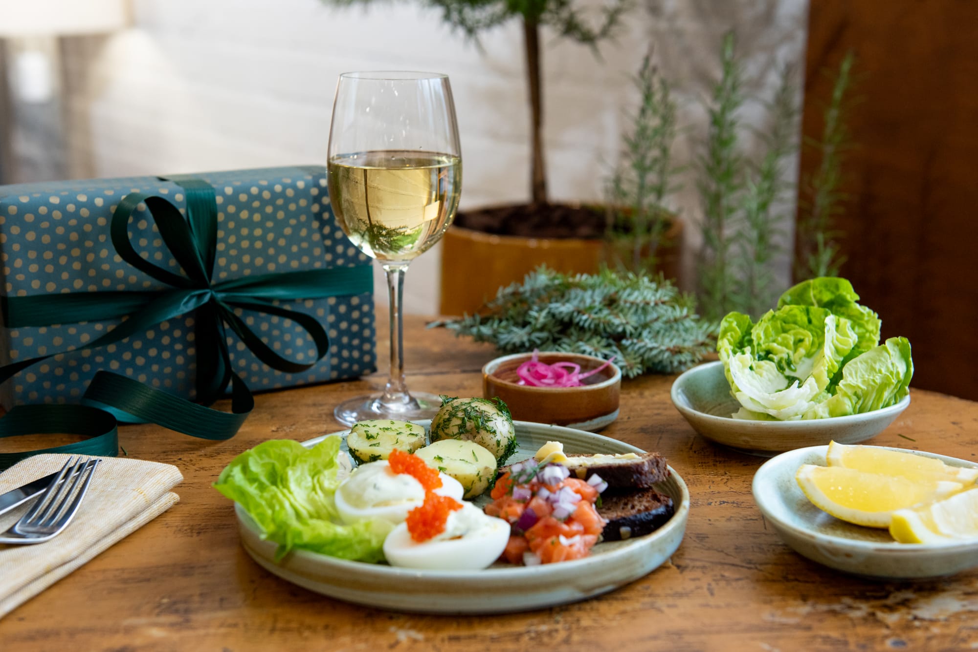 Lounaslautanen viinin ja lahjan kanssa pöydällä.