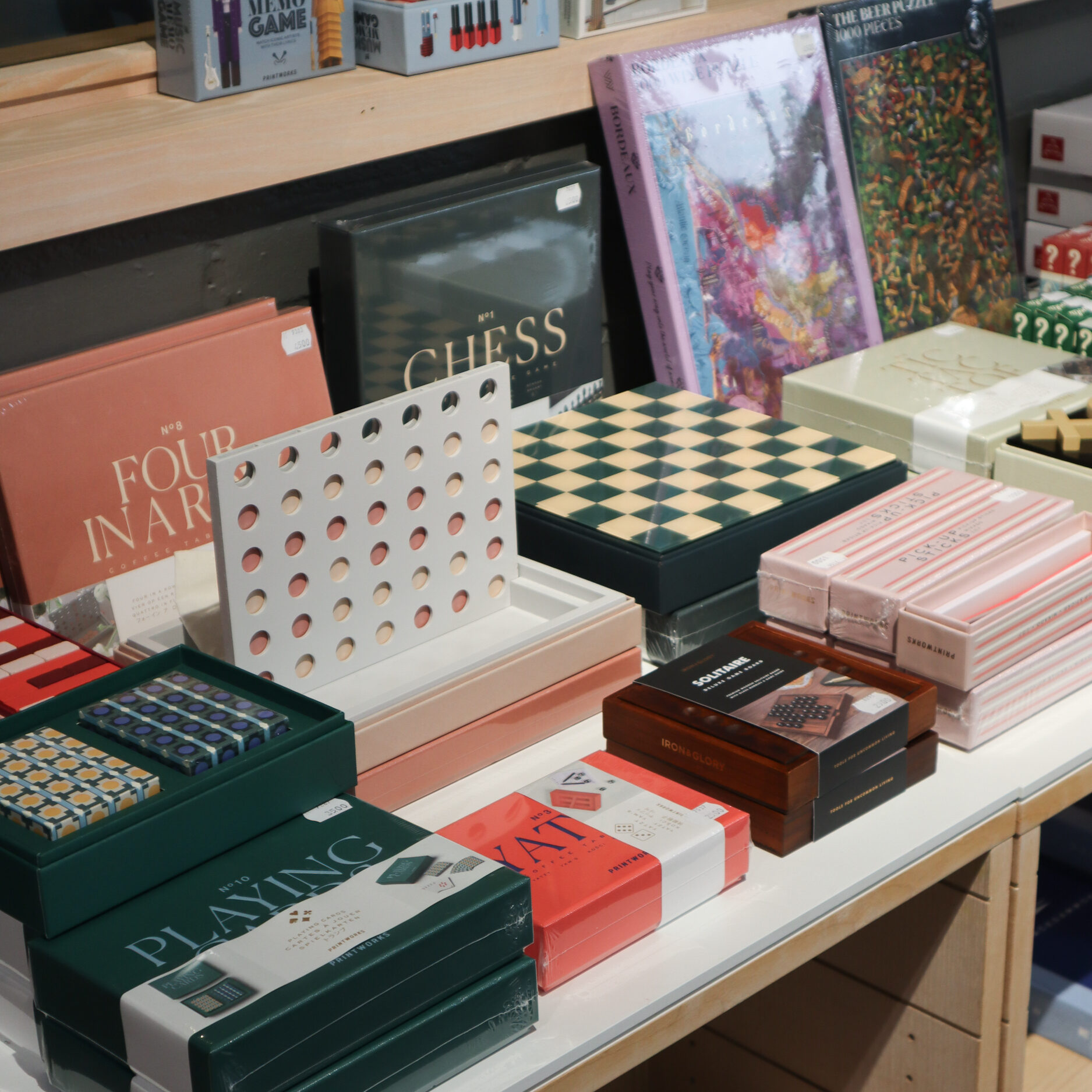 Pöydällä lautapelejä ja pulmapelikokoelmia myymälässä.