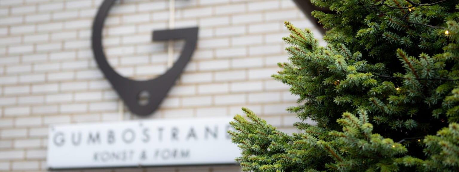 Tiiliseinä, havupuu ja kyltti 'Gumbostrand Konst & Form'