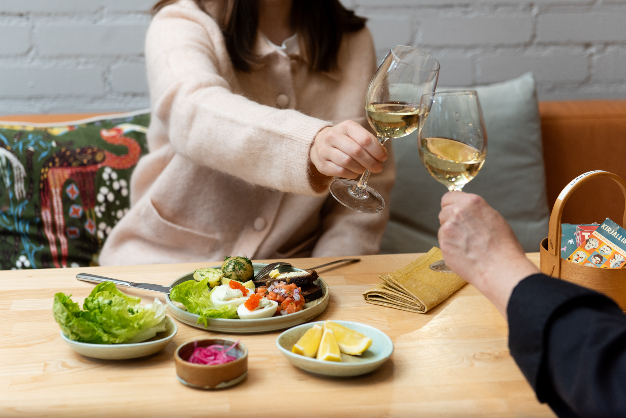 Kaksi henkilöä kippistelee viinilasien kanssa ravintolassa