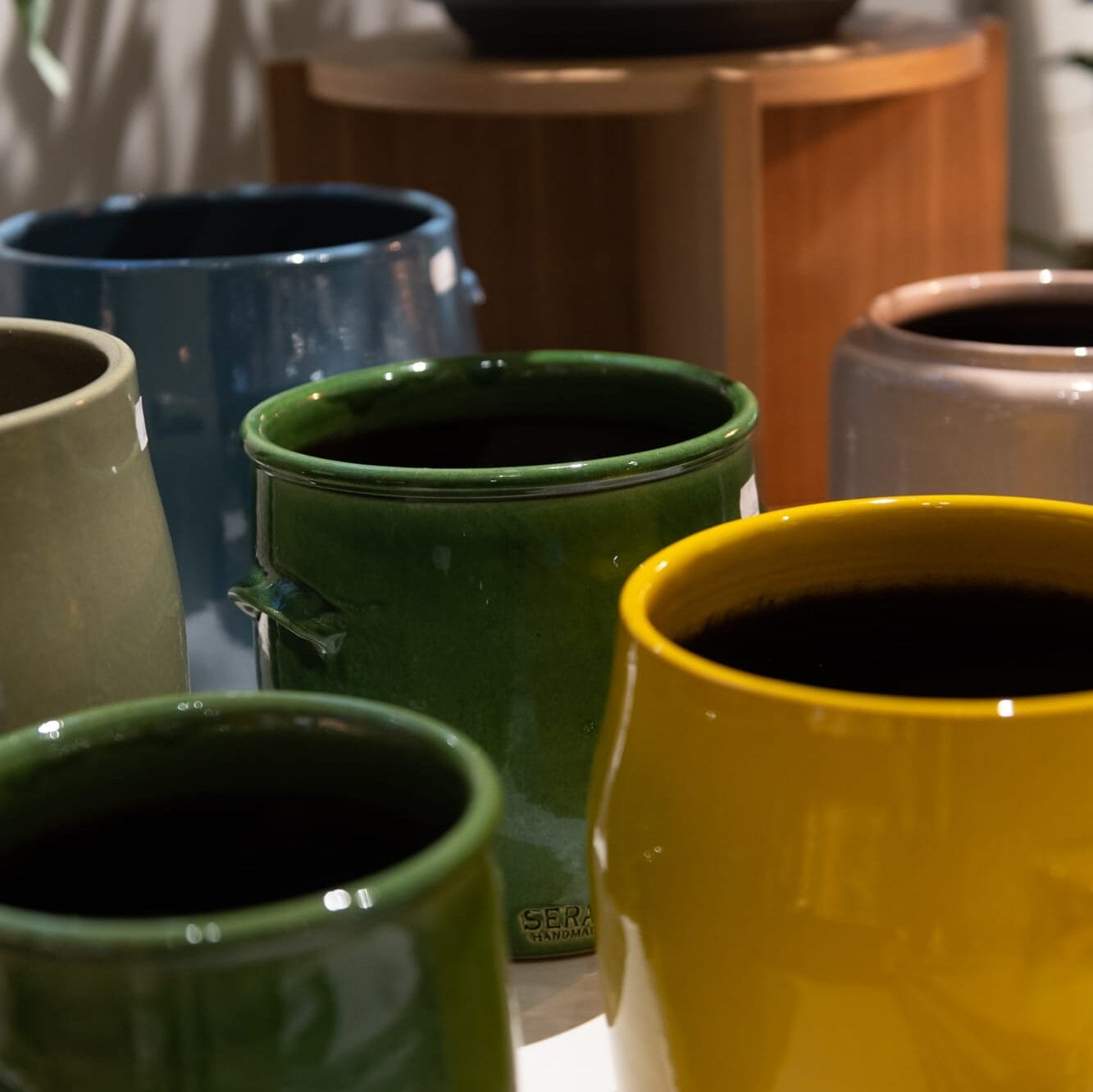 Erivärisiä keramiikkaruukkuja pöydällä