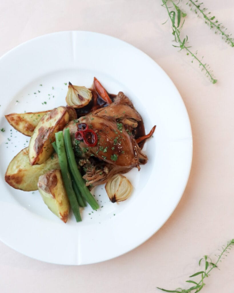 Paahdettu kana vihanneksilla ja perunoilla lautasella.