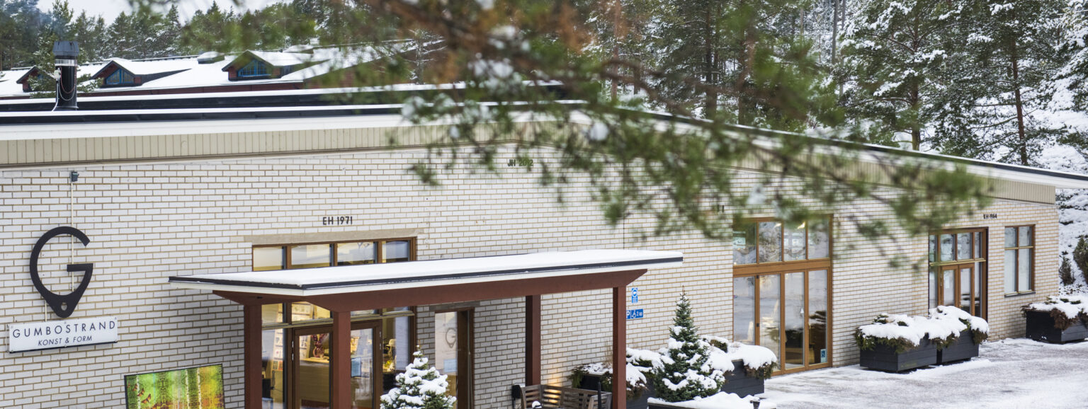 Snötäckt byggnad med skylt och granar