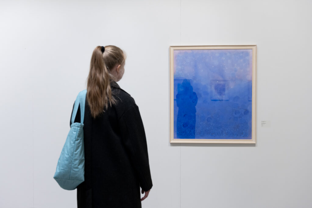 Nainen katsoo sinistä maalausta galleriassa