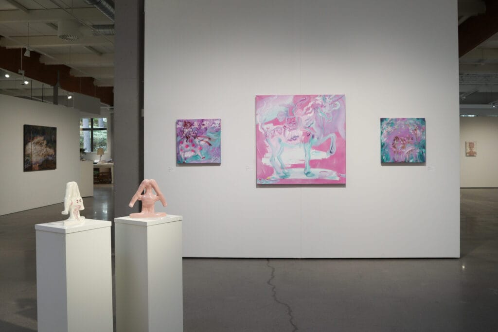 Taidenäyttely: veistoksia ja värikkäitä maalauksia galleriassa.