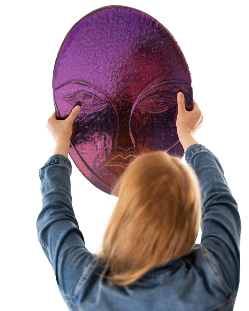 Nainen pitelee violettia kasvoveistosta käsissään.