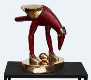 Punainen ja kultainen lintuveistos munan kanssa.