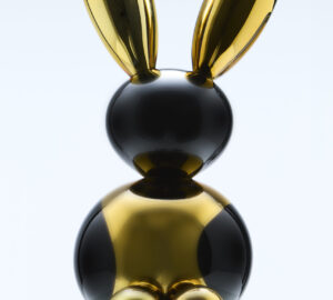 Kultainen ja musta jänisveistos marmorijalustalla.