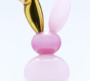 Vaaleanpunainen ja kultainen kaniinipatsas marmorialustalla.