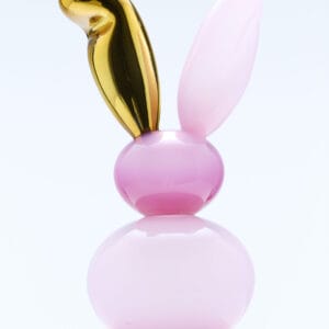 Vaaleanpunainen ja kultainen kaniinipatsas marmorialustalla.