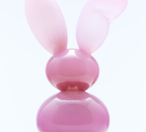 Vaaleanpunainen jäniksiksinä muistuttava veistos marmorijalustalla.