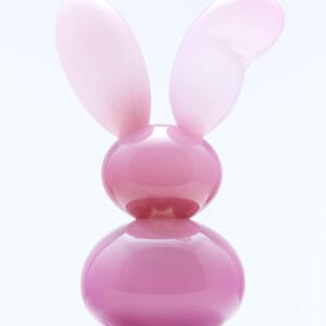 Vaaleanpunainen jäniksiksinä muistuttava veistos marmorijalustalla.