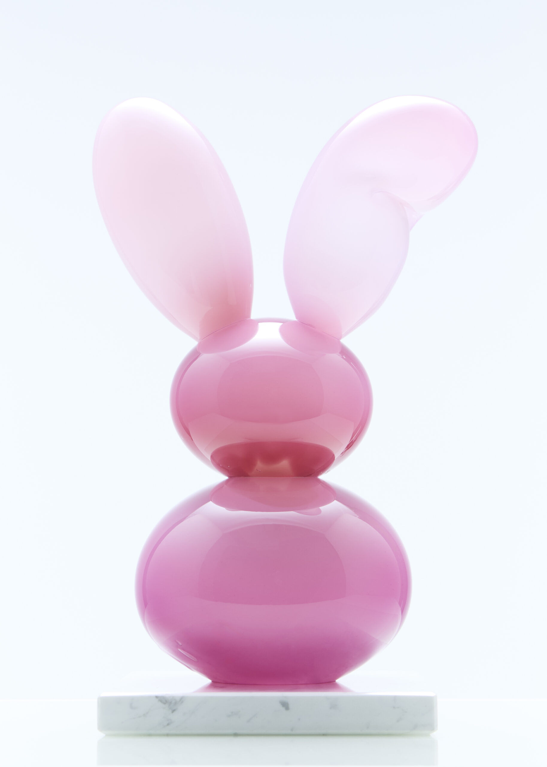 Vaaleanpunainen jäniksiksinä muistuttava veistos marmorijalustalla.