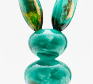 Vihreä lasipupu veistos marmorijalustalla.