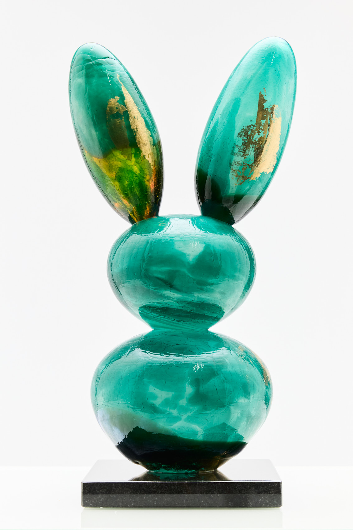 Vihreä lasipupu veistos marmorijalustalla.