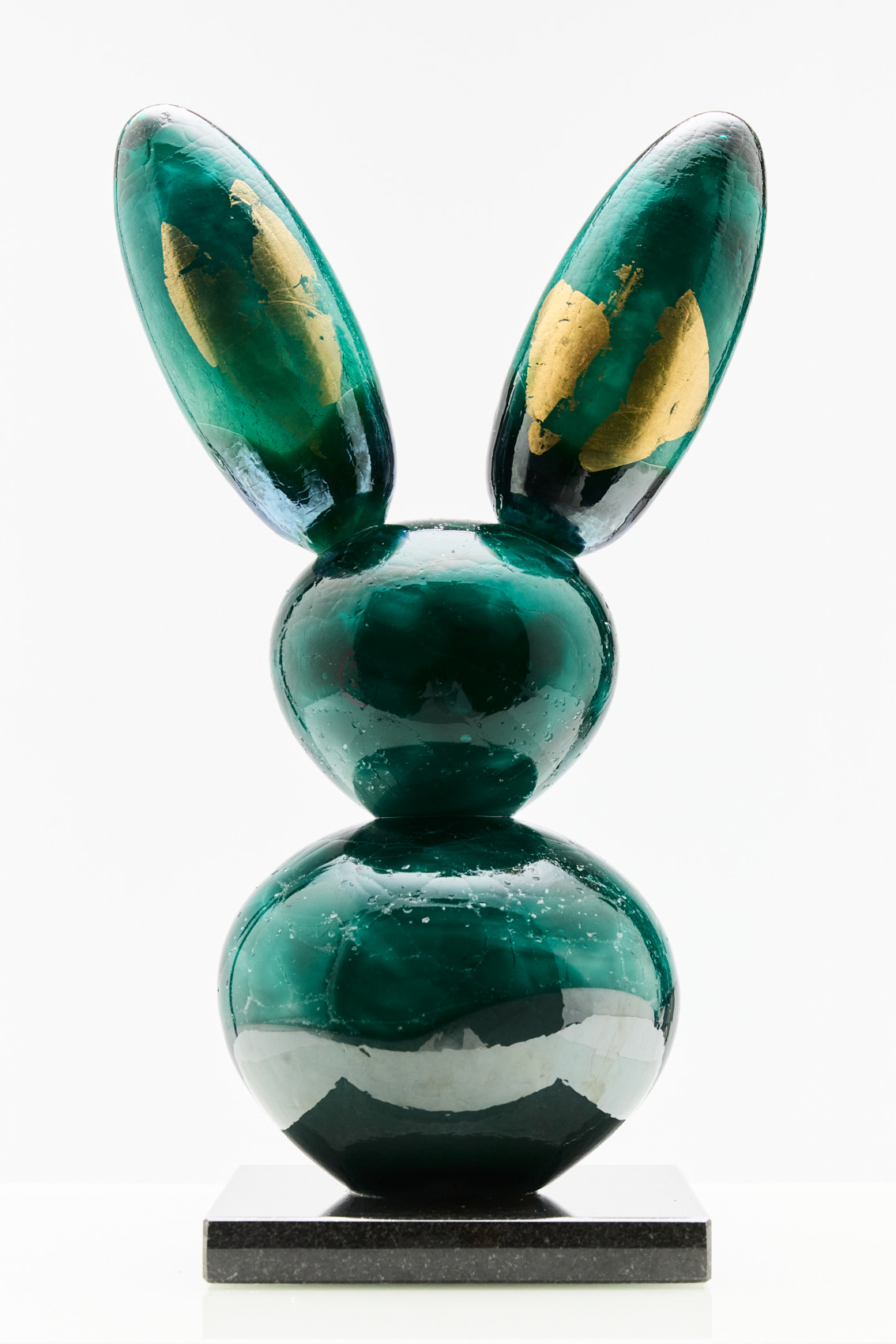 Vihreä pupuveistos kultaisilla yksityiskohdilla