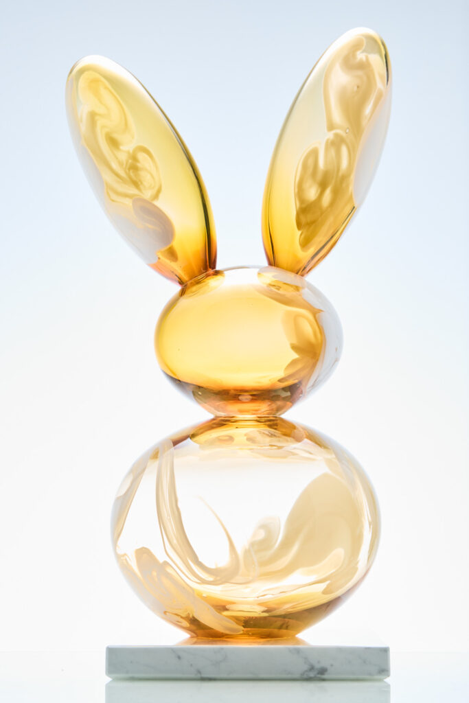 Lasipupu valkoisella alustalla, kultainen ja kiiltävä.