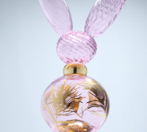 Vaaleanpunainen hajuvesipullo kultaisilla yksityiskohdilla