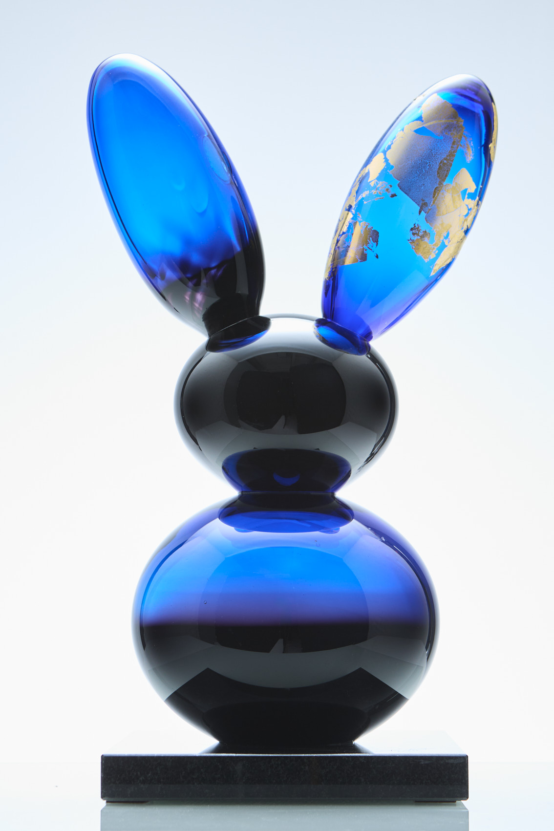 Sininen lasinen kanipatsas kultaisilla yksityiskohdilla.