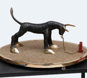 Pieni veistos härästä ketjussa hiekka-alustalla.