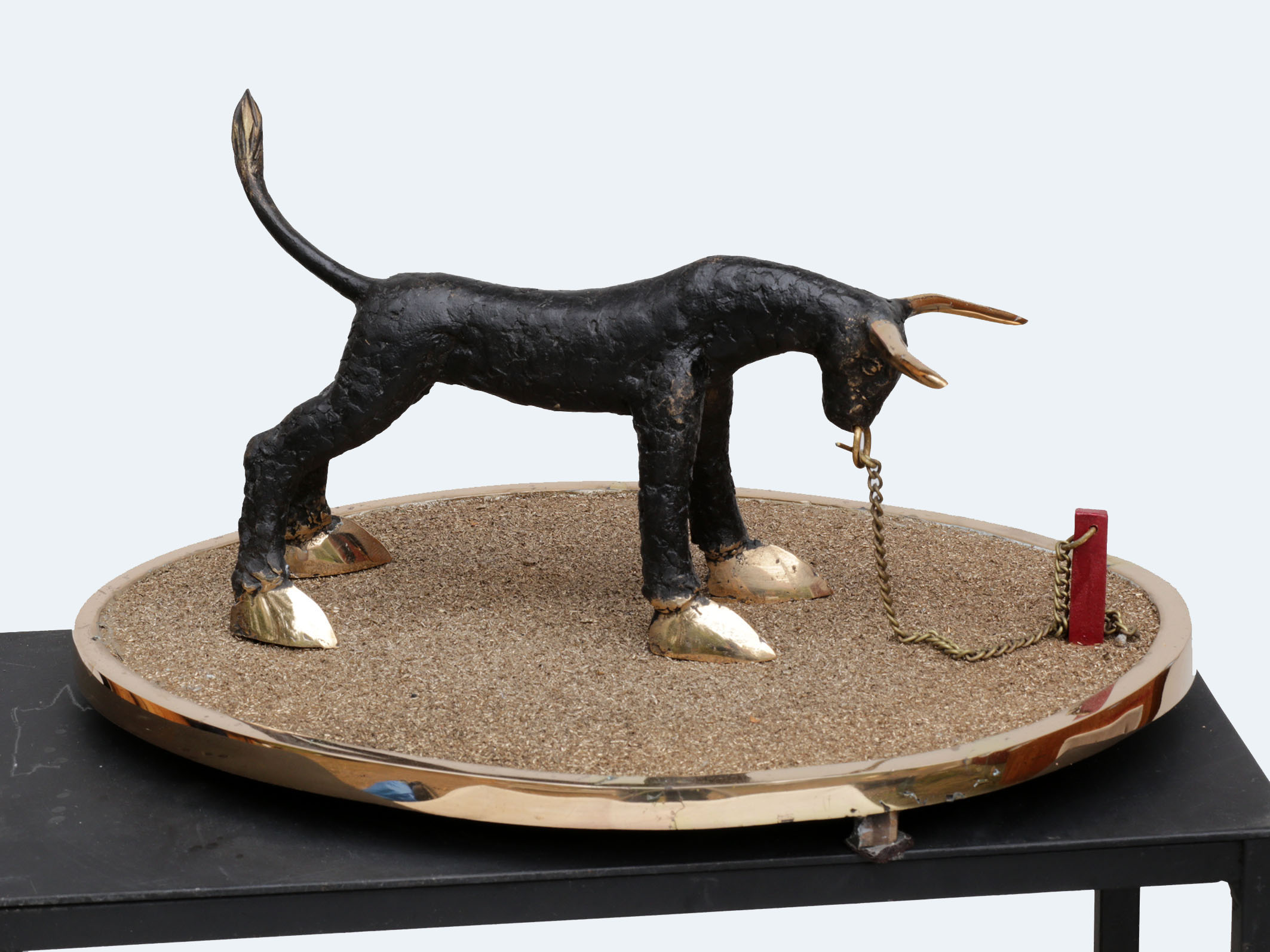 Pieni veistos härästä ketjussa hiekka-alustalla.