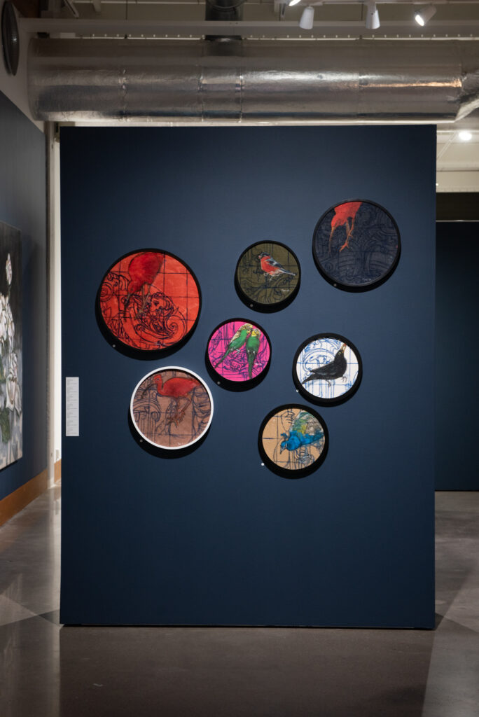 Seinällä värikkäitä pyöreitä taideteoksia näyttelyssä.