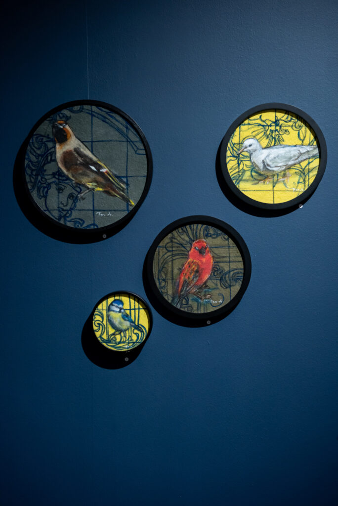 Neljä lintutaulua sinisellä seinällä.