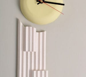Moderni seinäkello ja abstrakti veistos