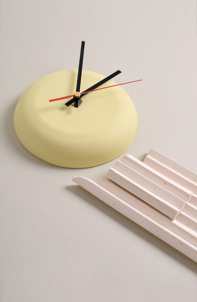 Keltainen seinäkello ja vaalea keramiikkakappale