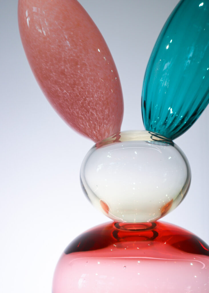 Värikäs lasiveistos valkoista taustaa vasten