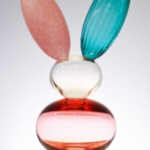 Monivärinen lasiveistos pupun korvilla