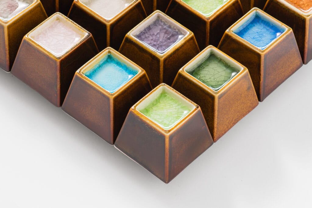 Värikkäät neliönmuotoiset keraamiset laatat valkoisella pinnalla.