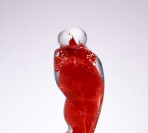 Punainen lasiveistos valkoisella taustalla