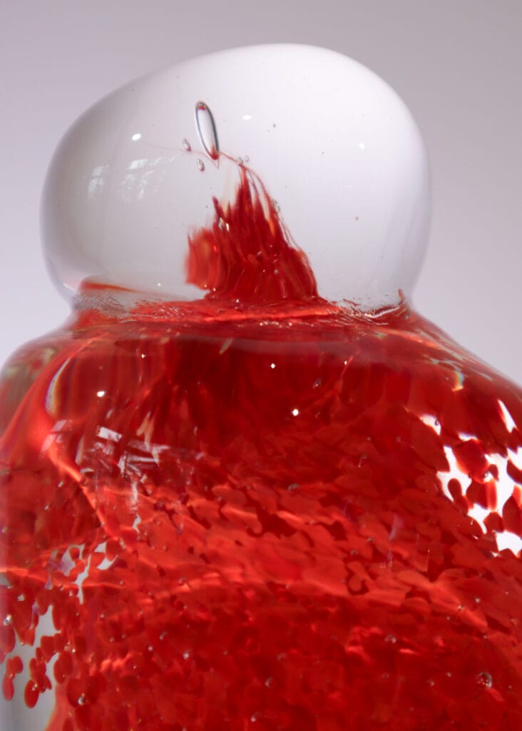 Punainen neste lasipullossa lähikuvassa.