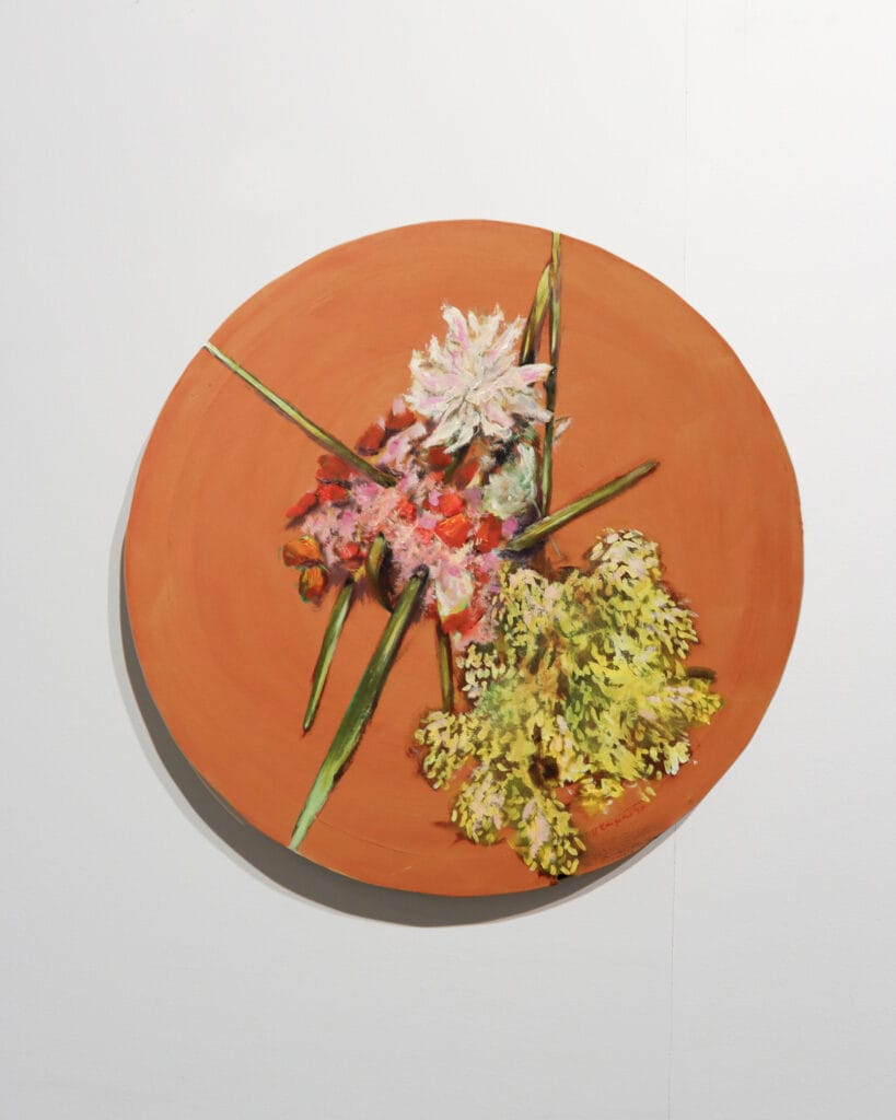 Kukkataulu oranssilla pyöreällä alustalla