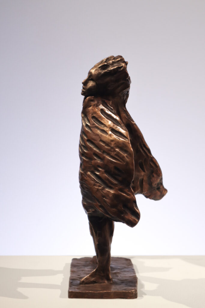 Pronssinen tuulinen patsas jalustalla.