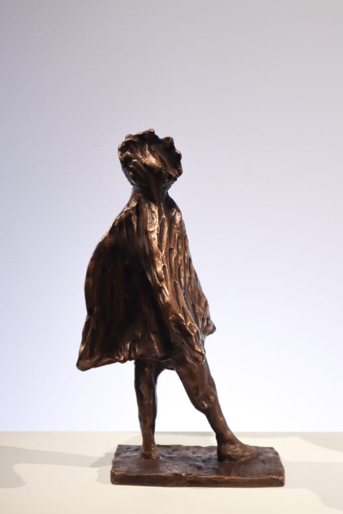 Pronssinen patsas kävelevästä lapsesta jalustalla.