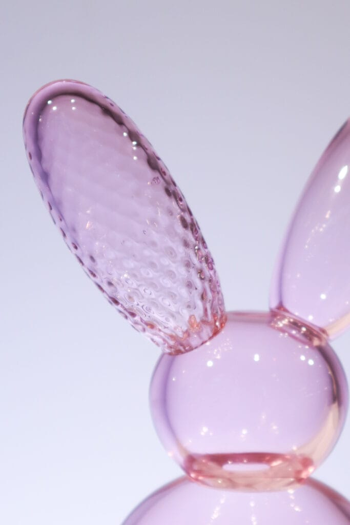 Vaaleanpunainen lasipupu vaalealla taustalla