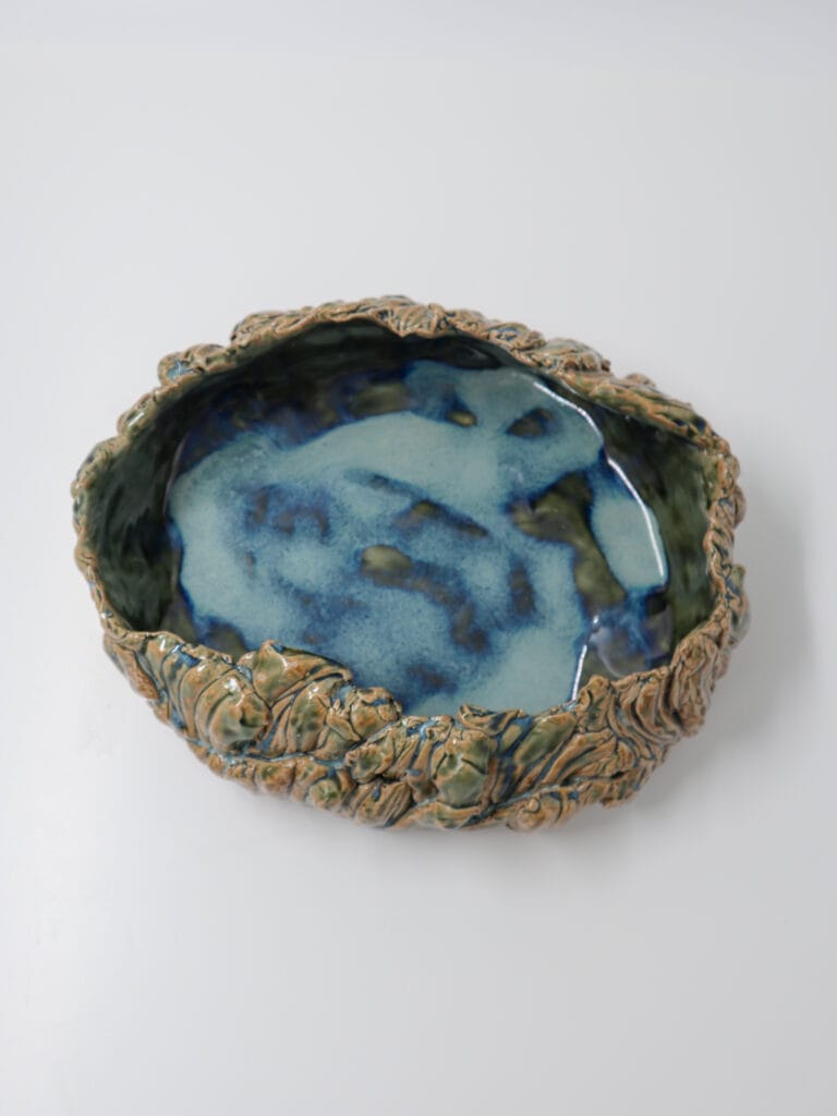 Käsintehty sininen keraaminen kulho koristeellisilla reunoilla.