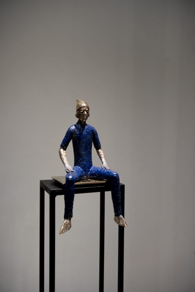 Sininen veistos miehestä istumassa jalustalla