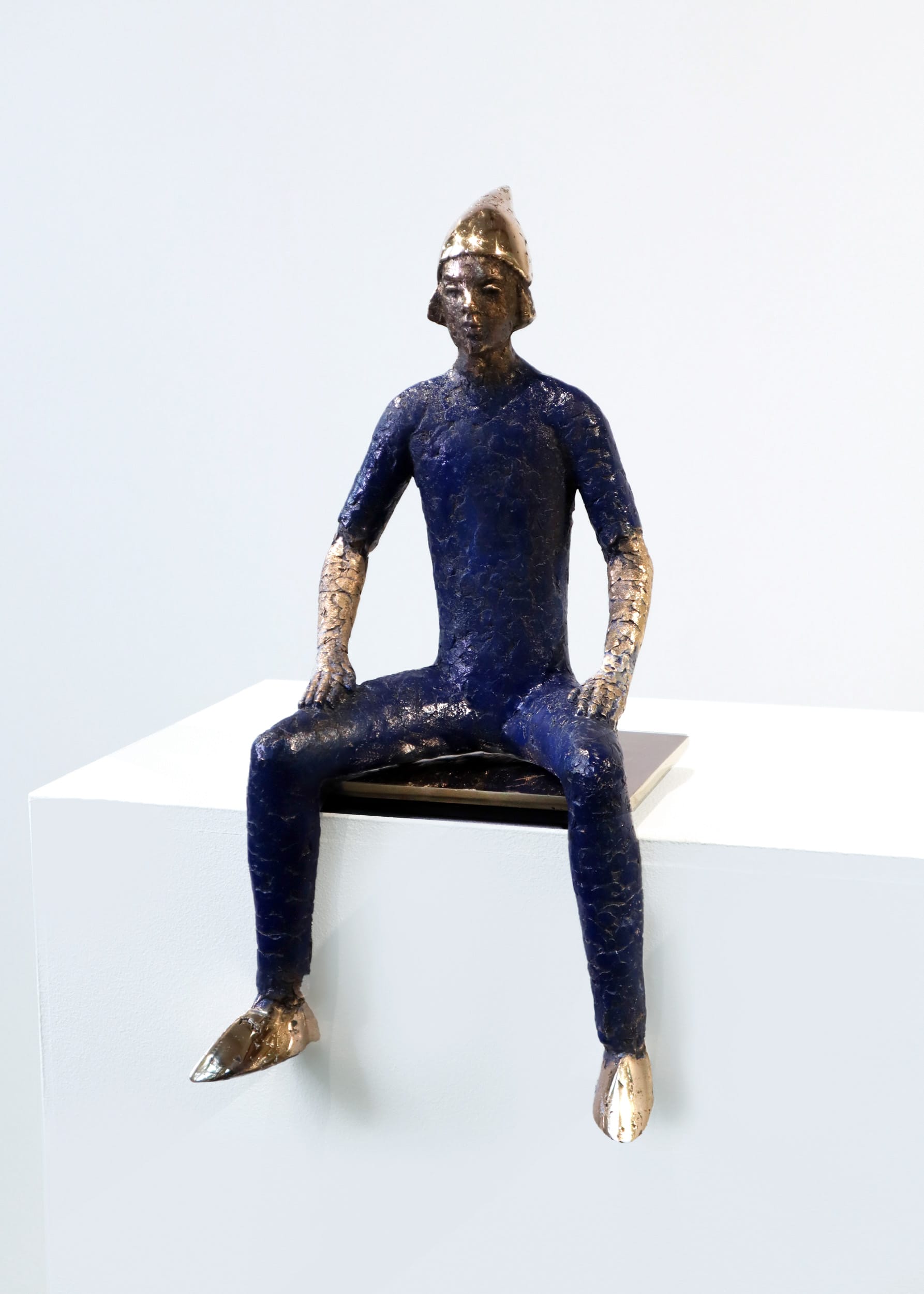 Sininen patsas kultakypärässä istuu jalustalla.