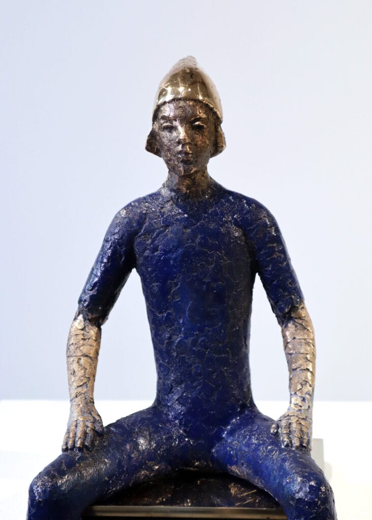 Sininen istuva patsas kypärällä näyttelyssä.