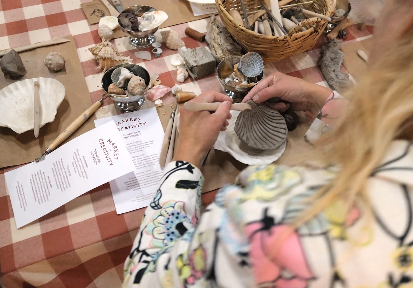 Taidepaja: henkilö muotoilee savikuorta työpöydällä.