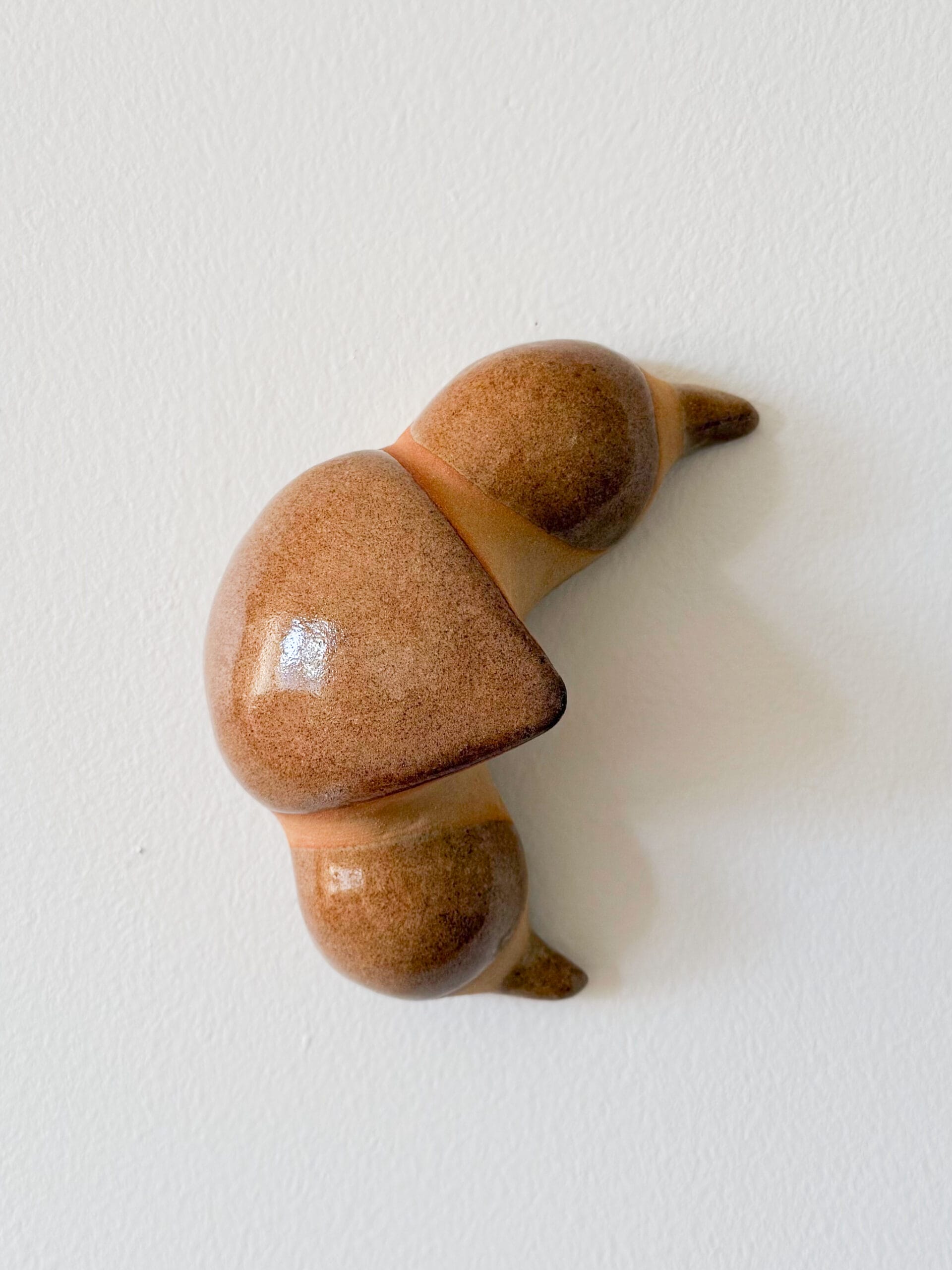 Ruskea keramiikkakoriste valkoisella seinällä