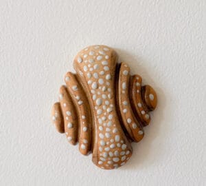 Keraaminen koriste valkoisella täpläkuviolla seinällä.