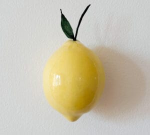 Keltainen sitruuna valkoisella seinällä.