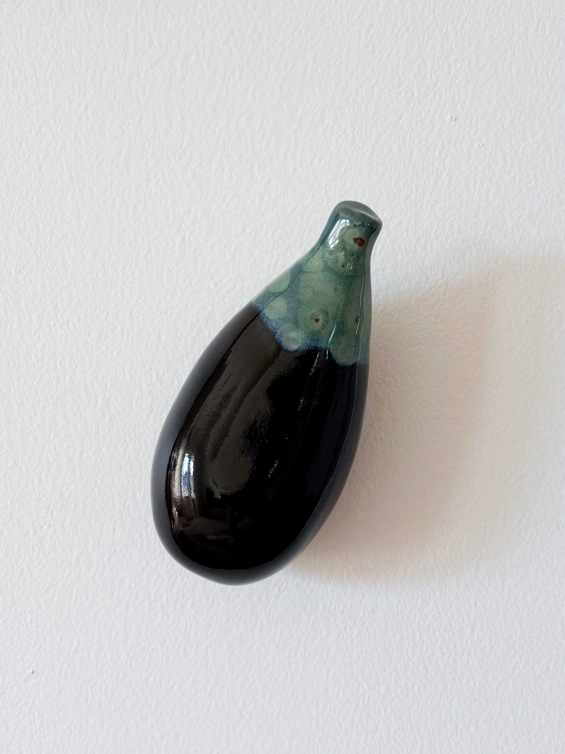 Mustavalkoinen keraaminen munakoiso vaalealla seinällä.